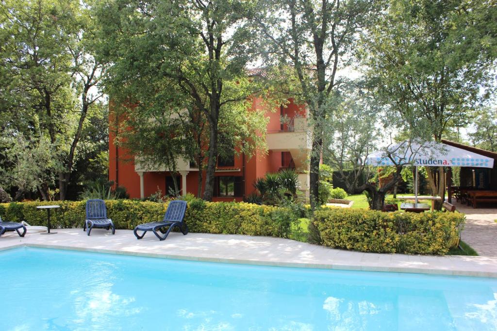 una piscina con due sedie e un edificio di Aqua Family Apartments a Karigador
