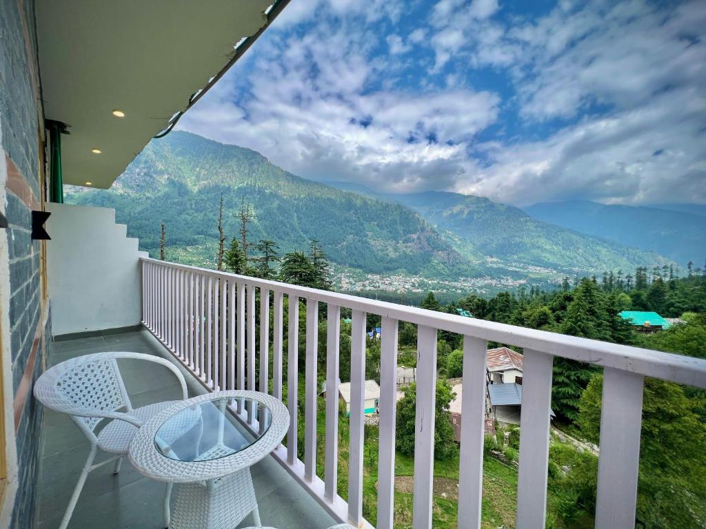 a balcony with a table and chairs and mountains at The Urban Retreat- A Boutique Hotel with Grand View in Manāli