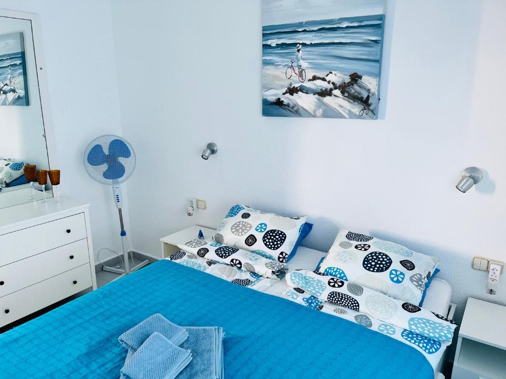 a bedroom with a blue bed with blue and white pillows at Oasis del Sol in Costa Calma