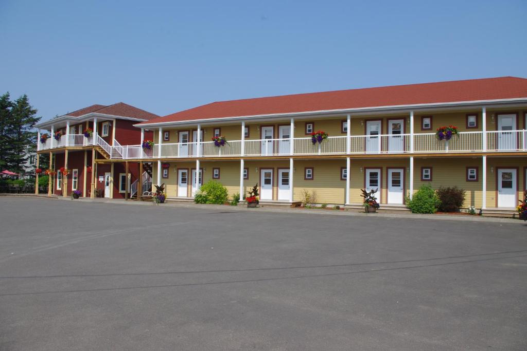 um grande edifício amarelo com um telhado vermelho em Motel des Mariniers em Kamouraska