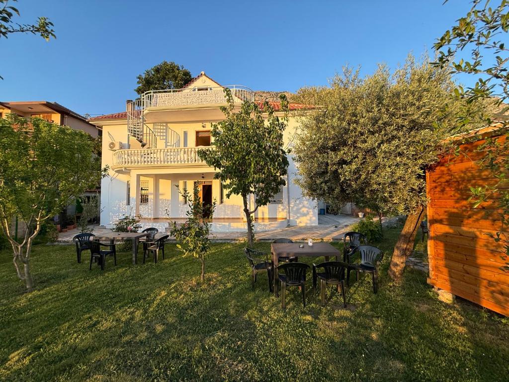 Meti Guest House في كرويه: مجموعة طاولات وكراسي امام المنزل