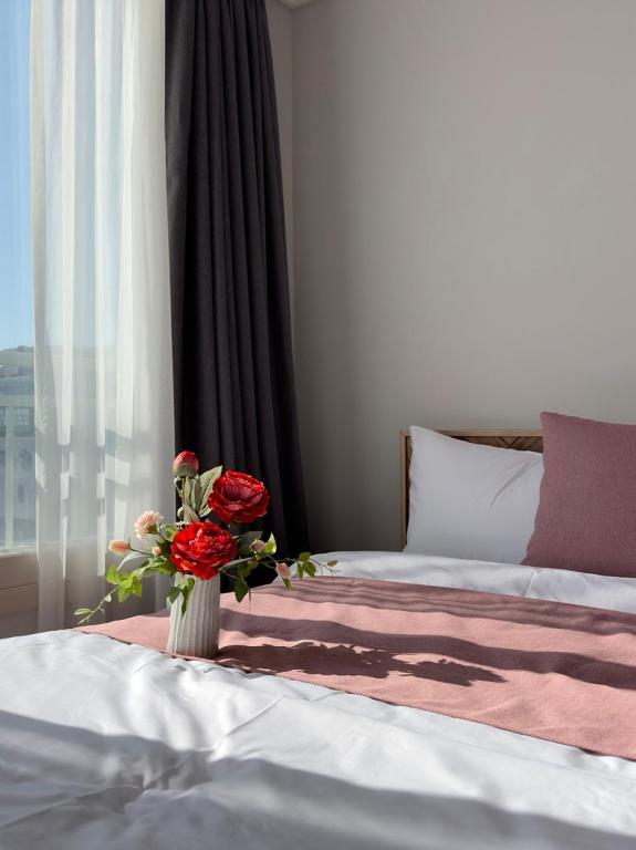 una camera da letto con un letto e un vaso di rose di Eunhasu D&M Residence a Daejeon