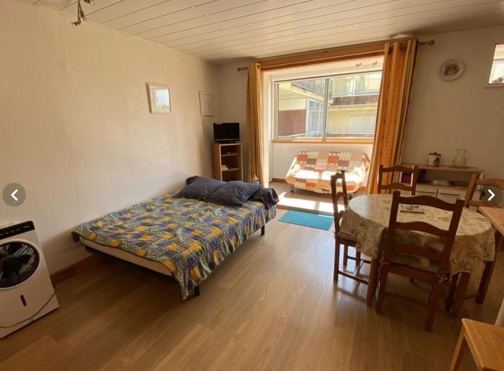 una camera da letto con un letto, un tavolo e una finestra di T1 meublé 300 m plage - 20 m des commerces ad Argelès-sur-Mer