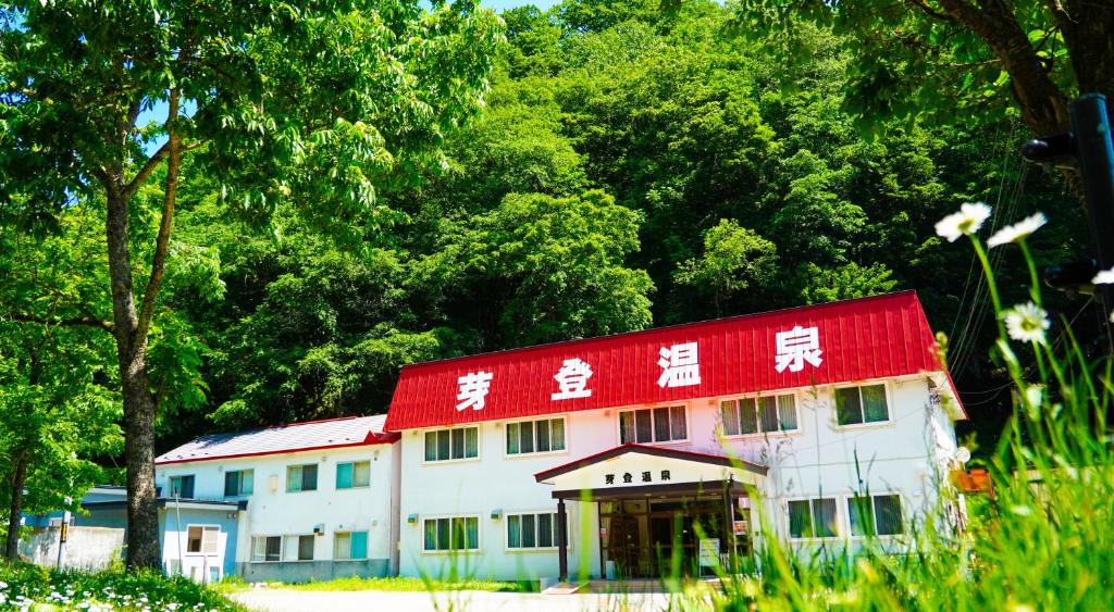 un bâtiment blanc avec un toit rouge devant des arbres dans l'établissement Metou Onsen Hotel, à Ashoro