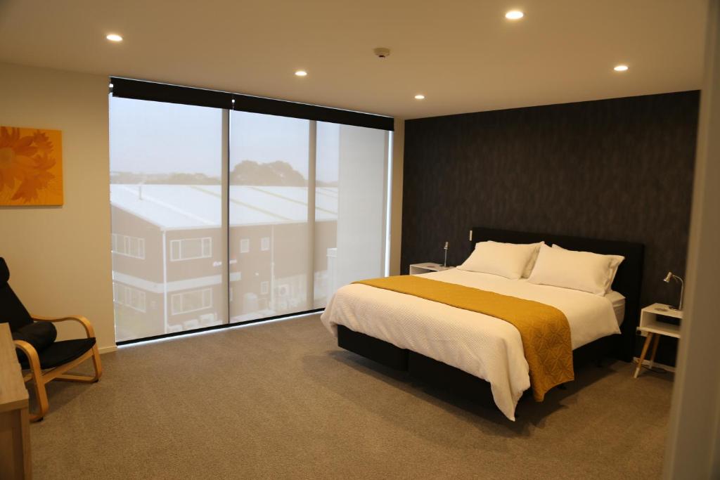 a bedroom with a large bed and a large window at Mountain View Townhouse, New Plymouth in New Plymouth