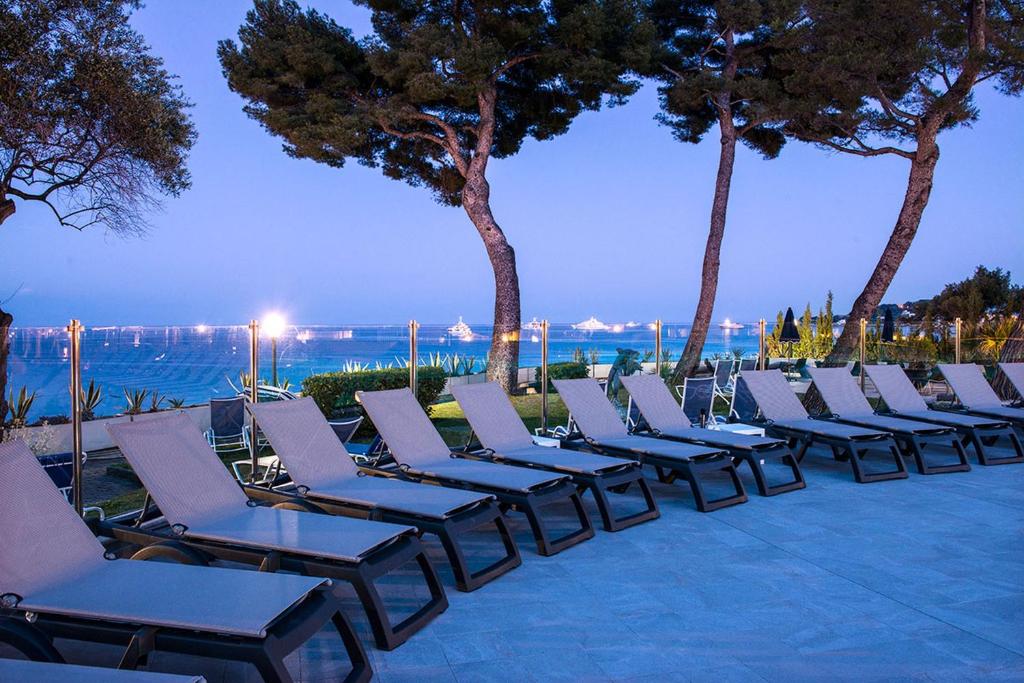 a row of lounge chairs on the beach at night at Hôtel Vacances Bleues Delcloy in Saint-Jean-Cap-Ferrat
