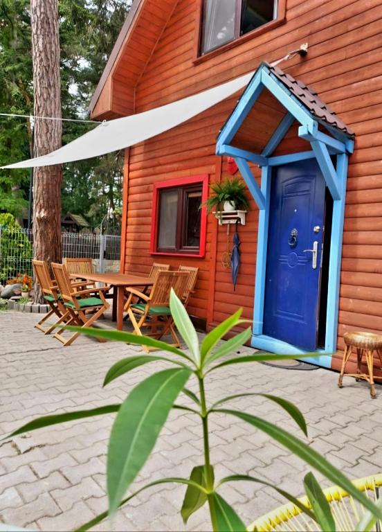 a house with a blue door and a table and chairs at Sosnowy domek in Pobierowo