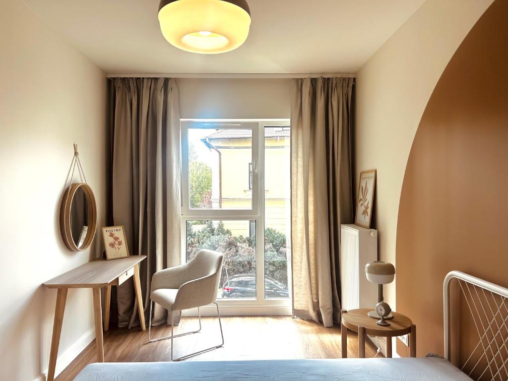 a bedroom with a bed and a desk and a window at Downtown Apartments Podpromie Monica with UNDERGROUND PARKING in Rzeszów