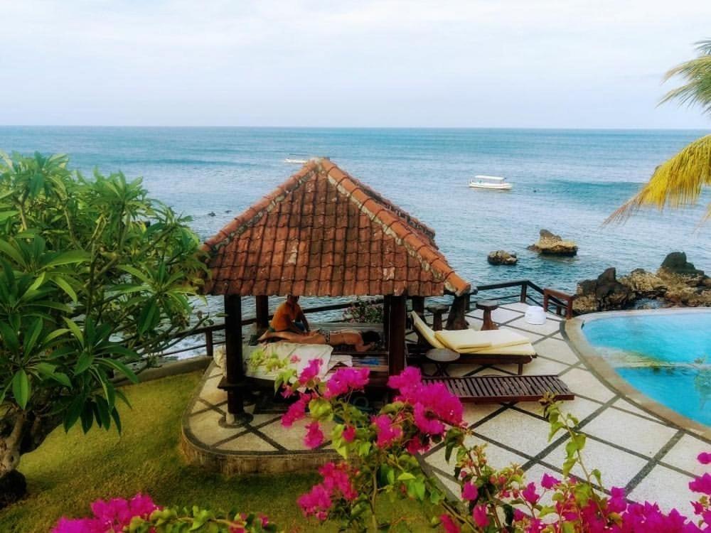a person sitting in a gazebo next to the ocean at Batu Belah Bungalows and Restaurant in Data