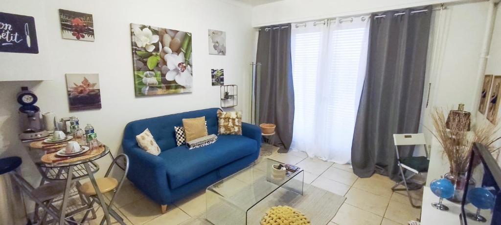 un salon avec un canapé bleu et une table dans l'établissement Nice Ouest, studio apartment near the beach, à Nice