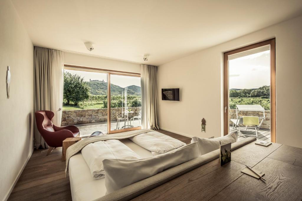 een slaapkamer met een groot bed en een groot raam bij MALAT Weingut und Hotel in Furth