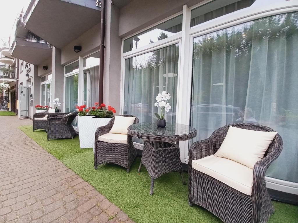 a patio with wicker chairs and a table on the grass at Pensjonat Plażowy Boss z Restauracją 50 metrów od Morza in Dziwnów