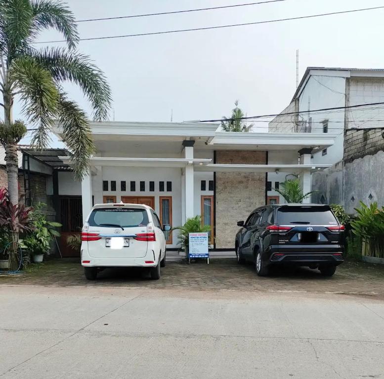 zwei Autos vor einem Haus geparkt in der Unterkunft Victoria Homestay in Pulau Lutung