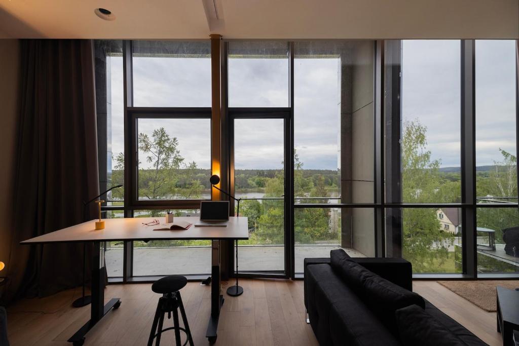 un soggiorno con un tavolo e una grande finestra di Design apartment with view to Nemunas, Prienai a Pakopi