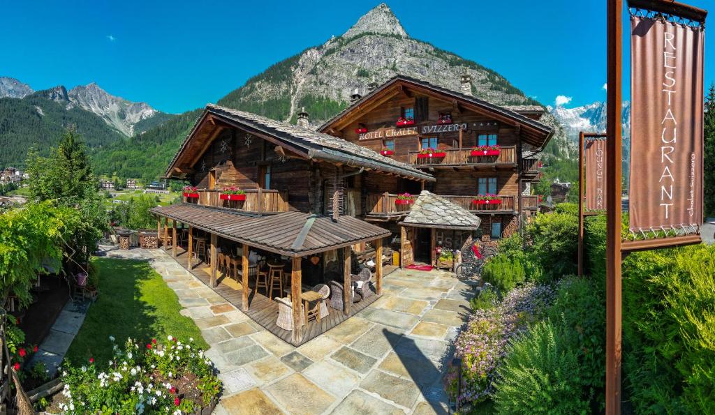 Ein großes Holzgebäude vor einem Berg im Hintergrund in der Unterkunft Chalet Svizzero in Courmayeur