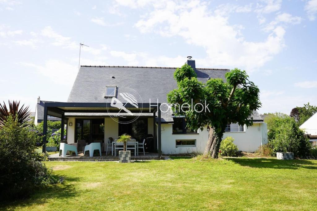 a white house with a tree in the yard at Magnifique maison de famille - Entre terre et mer in Fouesnant