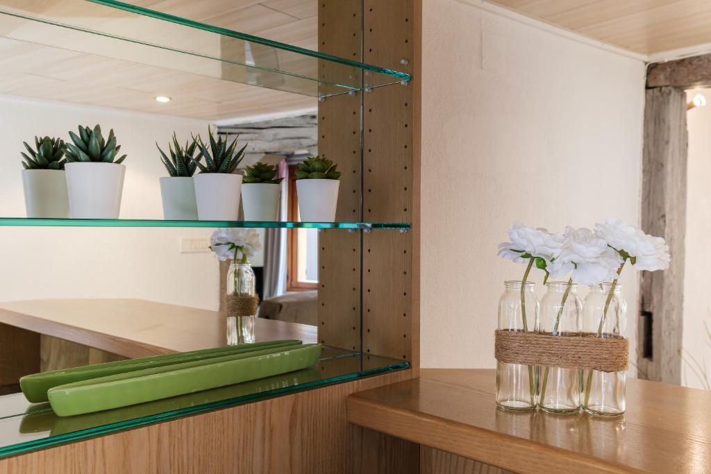 a glass shelf with flowers and vases on a table at Le studio in Turckheim
