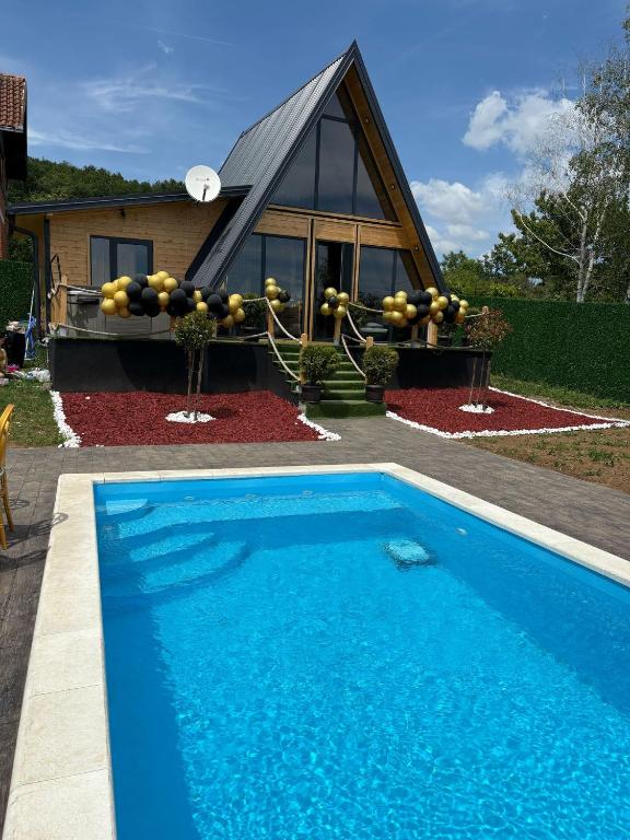 a house with a blue swimming pool in front of a house at A-Frame Wellness Villa with Private Pool, Sauna & Jacuzzi near Belgrade in Koraćica