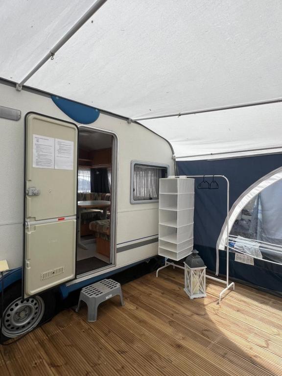 a blue and white trailer with a door open at Vintage przyczepa JustarniaCamp in Jastarnia