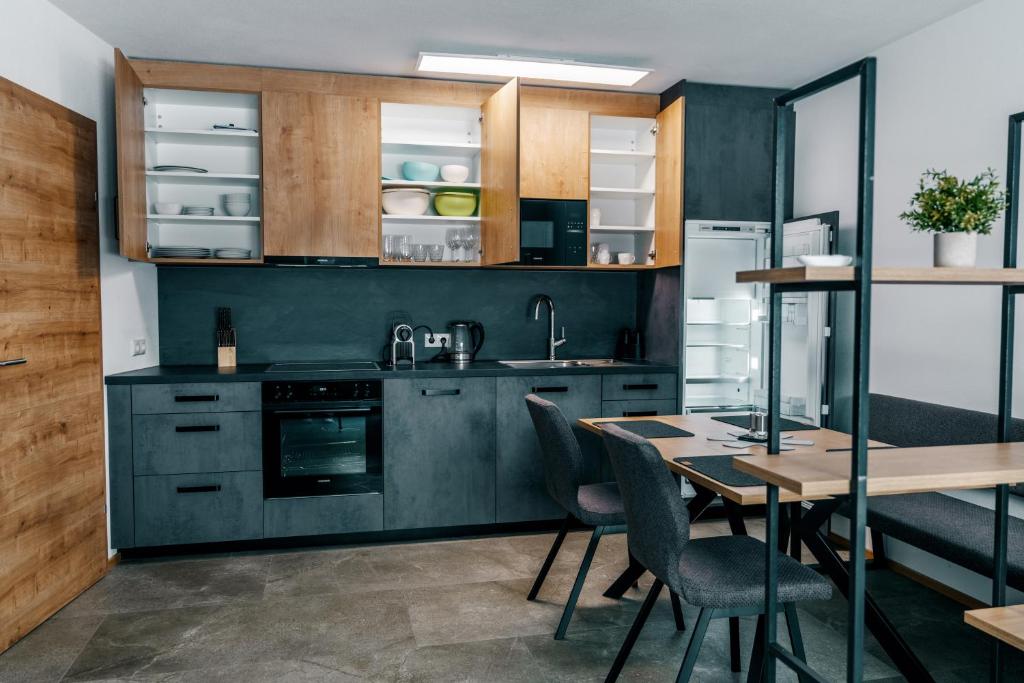 een keuken met houten kasten en een tafel met stoelen bij Danner Appartements Wolfsegg am Hausruck- Ferienwohnung & Business-Appartements Ruhige Lage, moderne Ausstattung, faire Preise in Wolfsegg am Hausruck