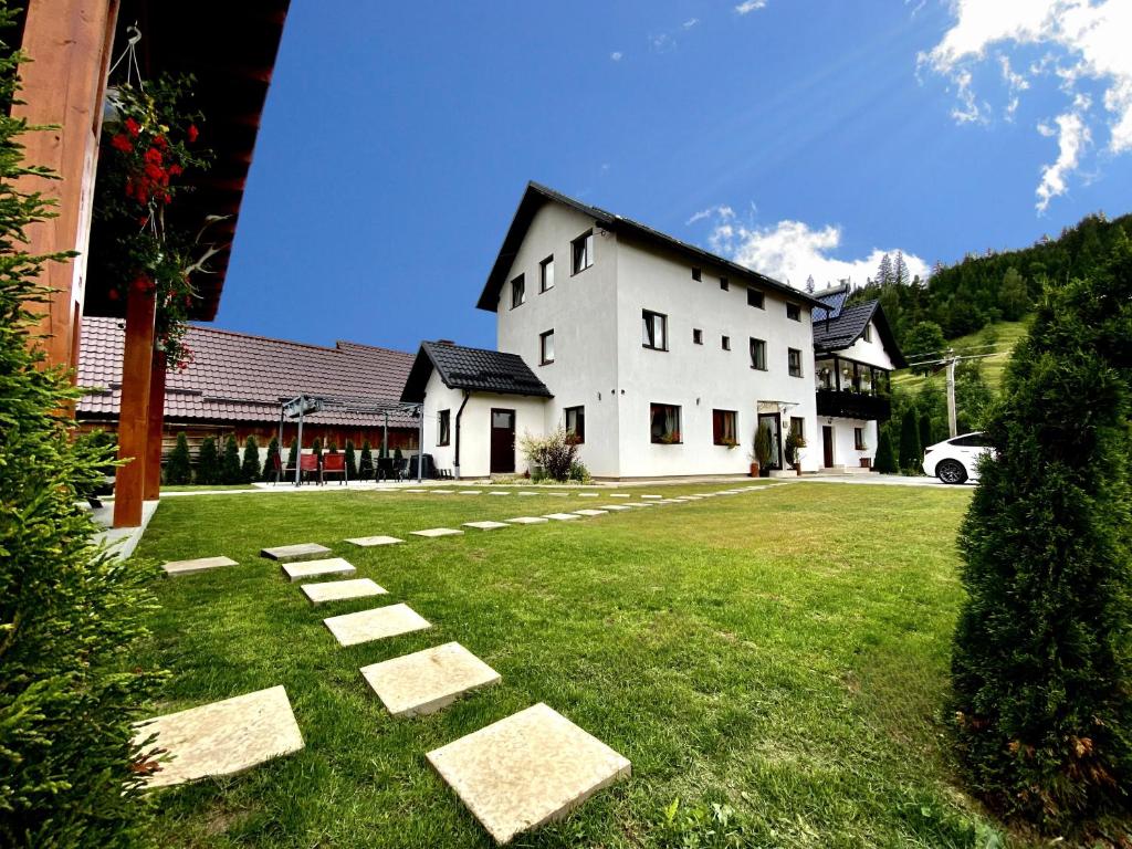 a large white house with stepping stones in the grass at Casa Ambra in Sadova