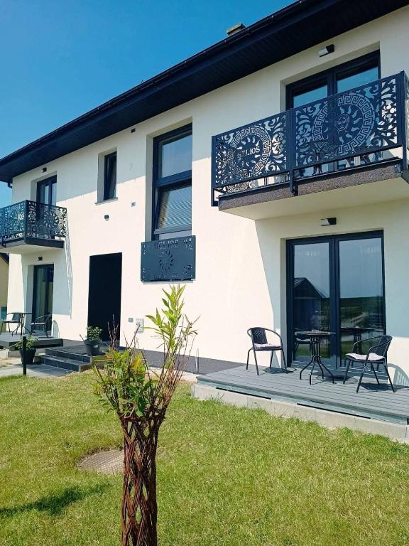 a house with a balcony and a table and chairs at Dom Gościnny Helios in Mielno