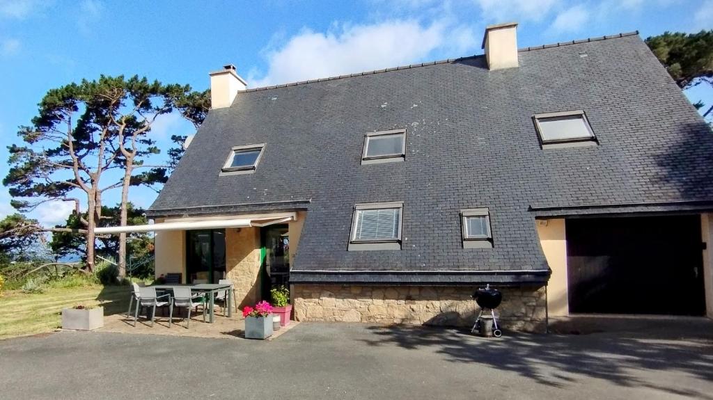 a house with a gray roof and a table at Spacieuse maison familiale proche de la mer in Penvénan