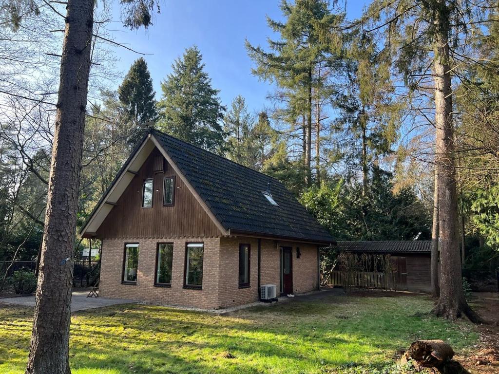 a small house with a black roof in a yard at Forest house with sauna in Norg