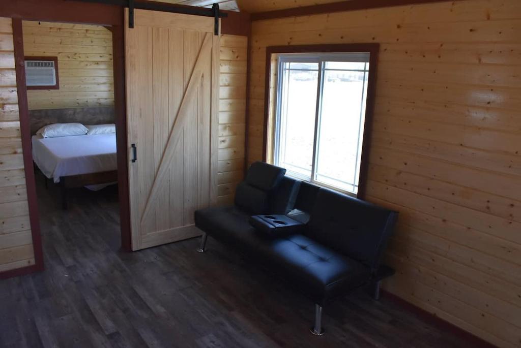 a room with a chair and a bed and a window at Charming small cabin in Floydada
