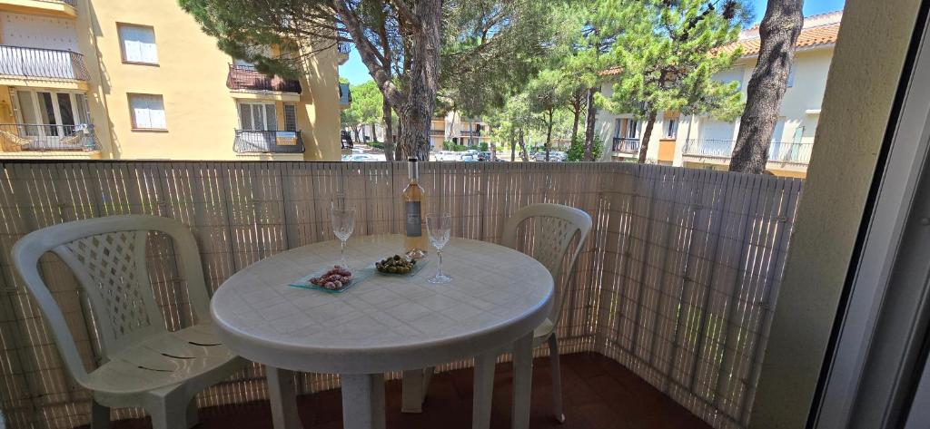- une table et des chaises blanches avec une bouteille et des verres à vin dans l'établissement T2 MER ET PLAGE A 300 mètres, à Argelès-sur-Mer