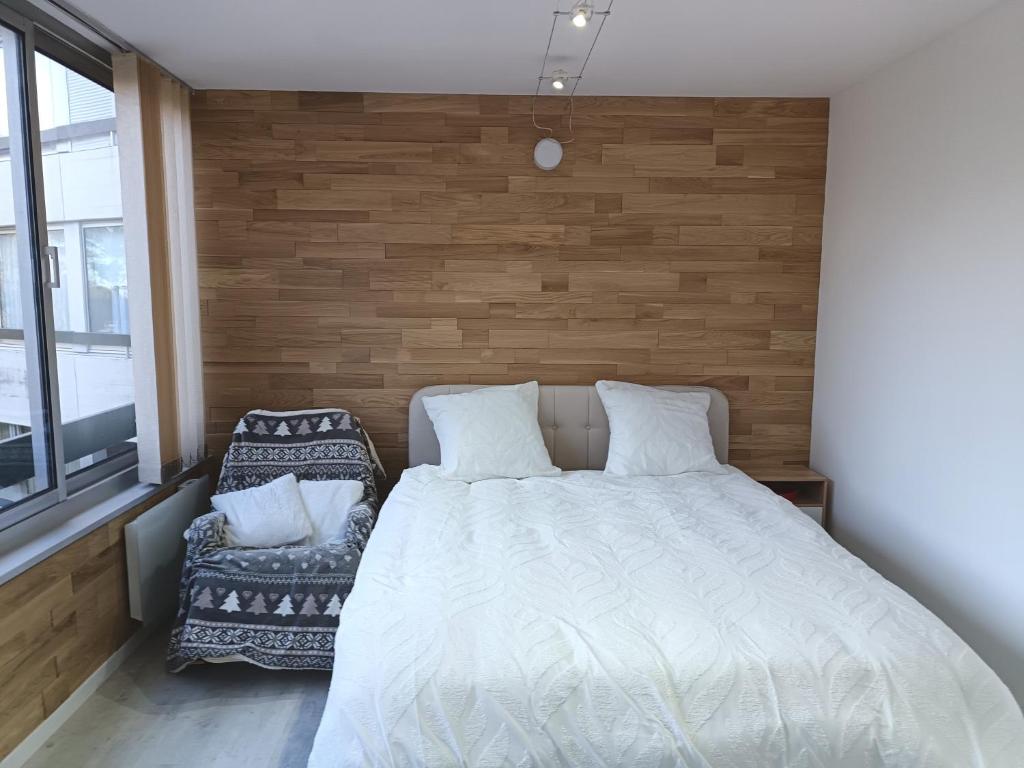 een slaapkamer met een bed en een stoel bij Se détendre Au Petit Epi in Turckheim