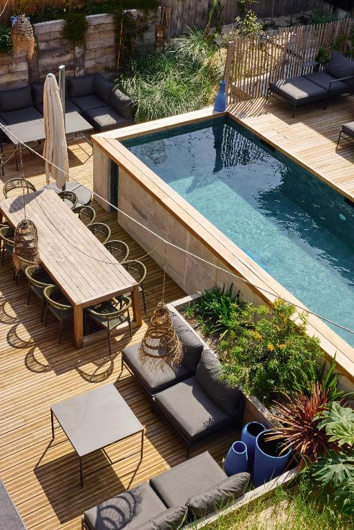 - une piscine avec une table, des chaises et un banc dans l'établissement Kaze Océan, The Originals Relais, à Cap-Ferret