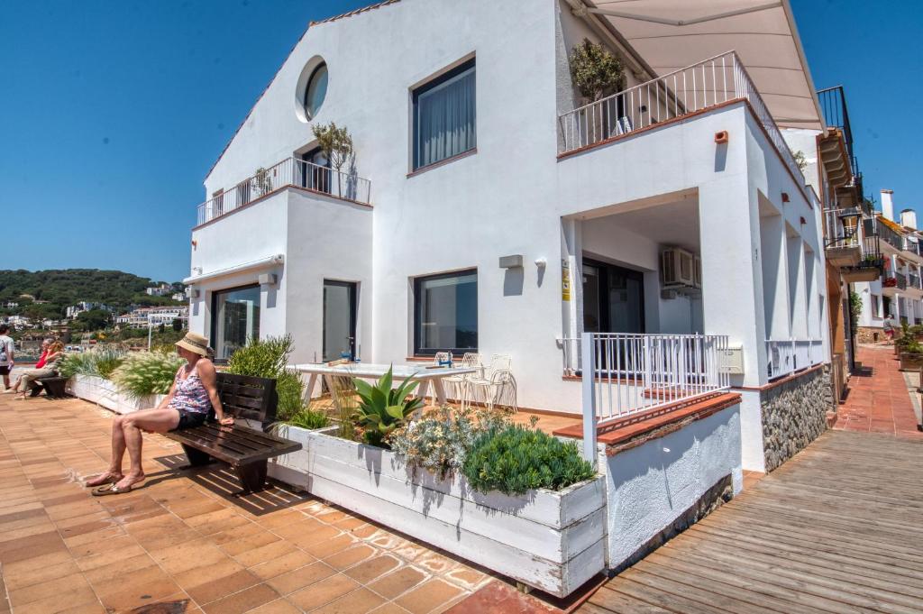 a woman sitting on a bench in front of a building at House in the sea in Calella de Palafrugell