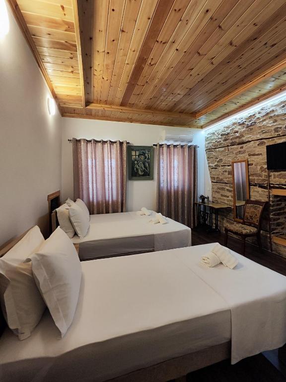 a bedroom with two beds and a stone wall at Rest & View Guesthouse in Gjirokastër