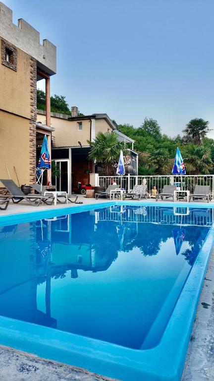 a large blue swimming pool with chairs and umbrellas at Apartments Ljiljanic in Budva