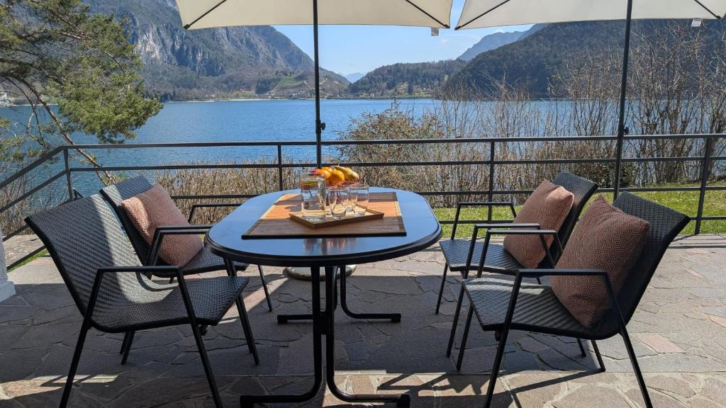 梅佐拉戈Ledro Casa Pino al Lago mit direktem Seezugang的庭院配有桌椅和遮阳伞。