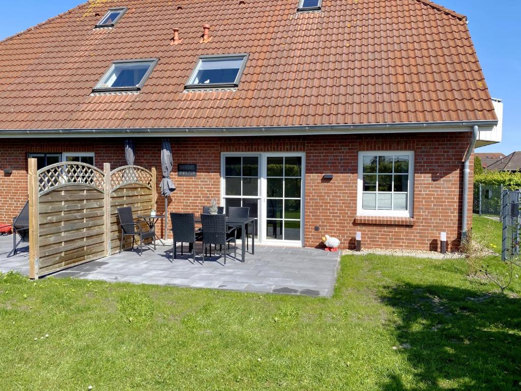 ネスマージールにあるNessmersiel, Renovierte Erdgeschosswohnung mit Garten, in Deichnähe, Wallbox,のレンガ造りの家で、パティオ(テーブル、椅子付)が備わります。