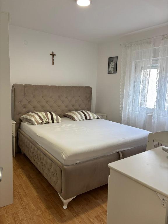 1 cama en un dormitorio con una cruz en la pared en ivsevo greblje, en Ivišovo Greblje