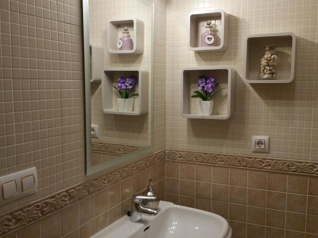 uma casa de banho com lavatório, espelho e flores roxas em Apartamento Capitania em Granada
