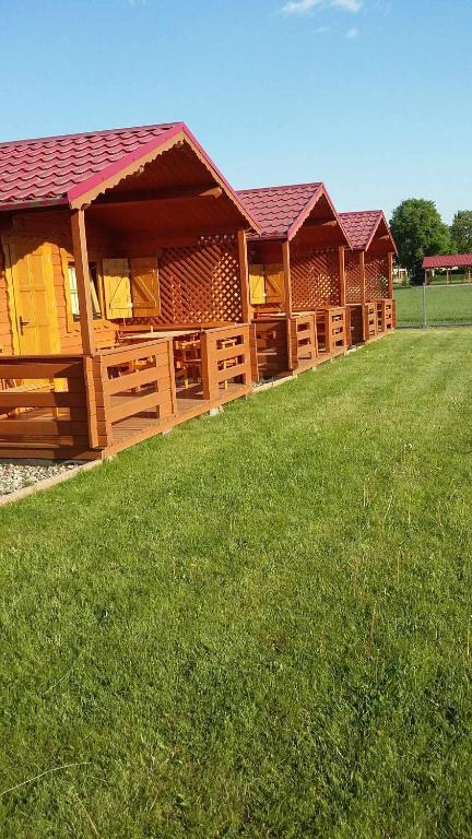 a row of wooden buildings on a grass field at Domki letniskowe Wrzoski in Kamień Pomorski
