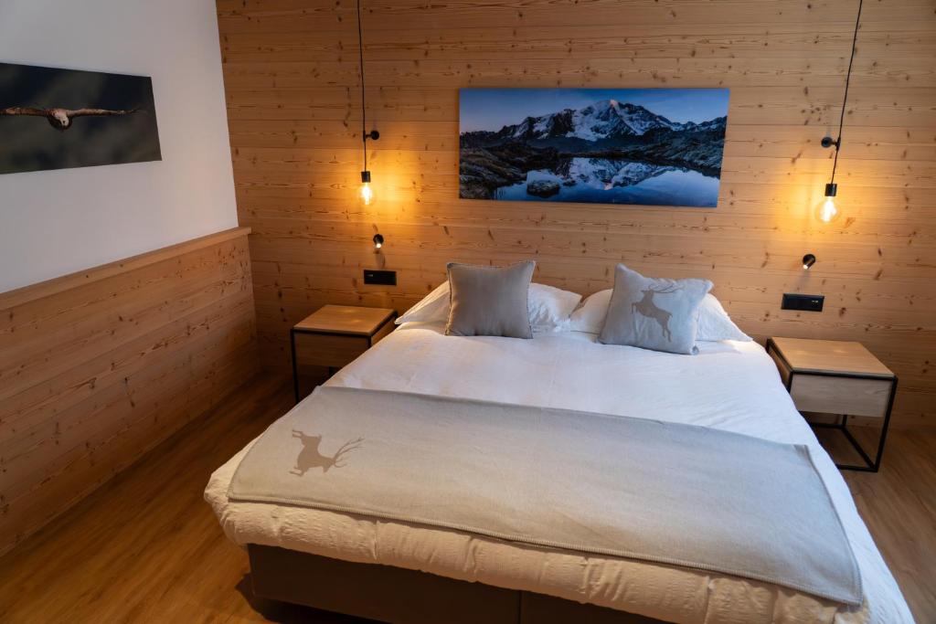 a bedroom with a large white bed with two tables at Hotel Les Chamois in Verbier