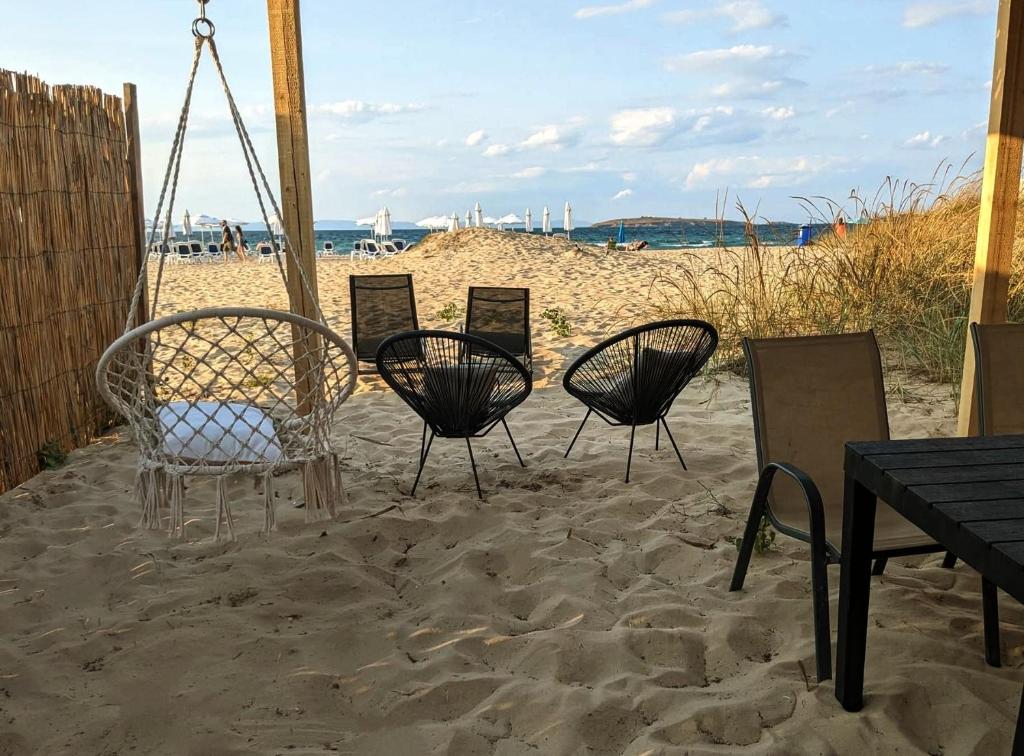 four chairs and a table in the sand at the beach at Каравана The Jungle in Chernomorets