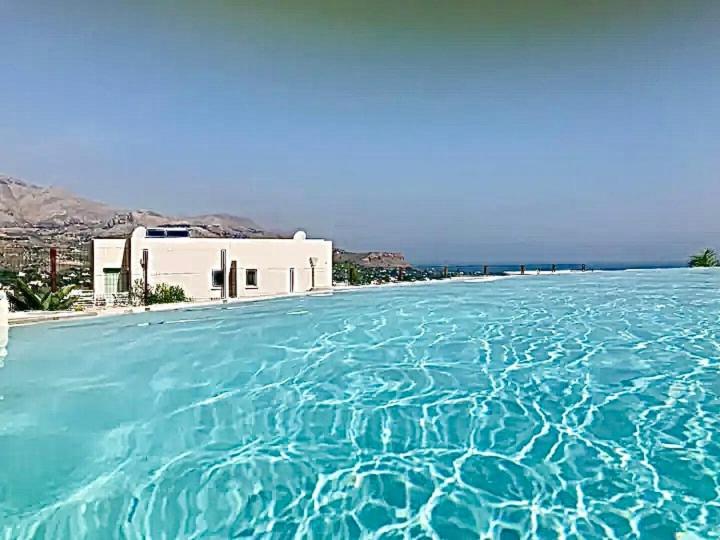 une grande piscine d'eau bleue devant un bâtiment dans l'établissement Giardino degli Allori, Villa Manfredi with Pool, à Castellammare del Golfo