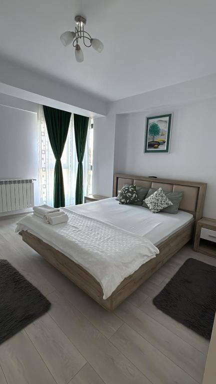 a bedroom with a large white bed with green curtains at Apartamentul Verde in Tulcea