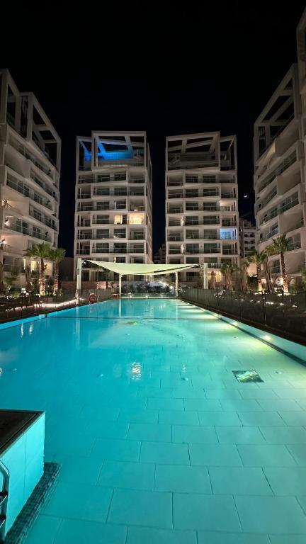 a large swimming pool at night with tall buildings at Lotus Suite 42 in Eilat