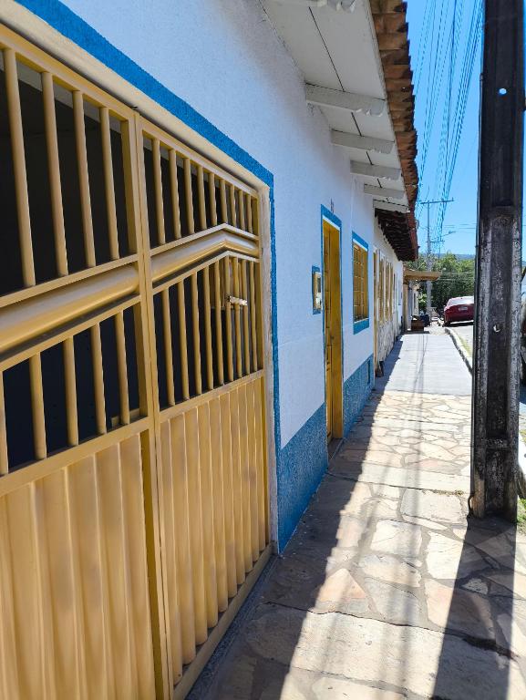 a blue and white building with yellow doors and a sidewalk at Casa Lilás in Goiás