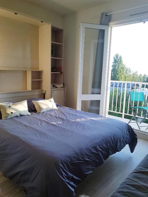 - une chambre avec un lit bleu et une grande fenêtre dans l'établissement Studio vacances pour 2, 300m de la plage, vue sur la mer, à La Guérinière