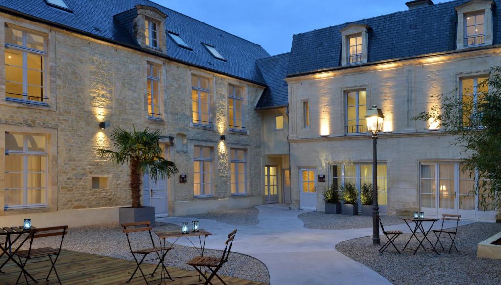 um pátio com mesas e cadeiras em frente a um edifício em La Maison de Mathilde em Bayeux