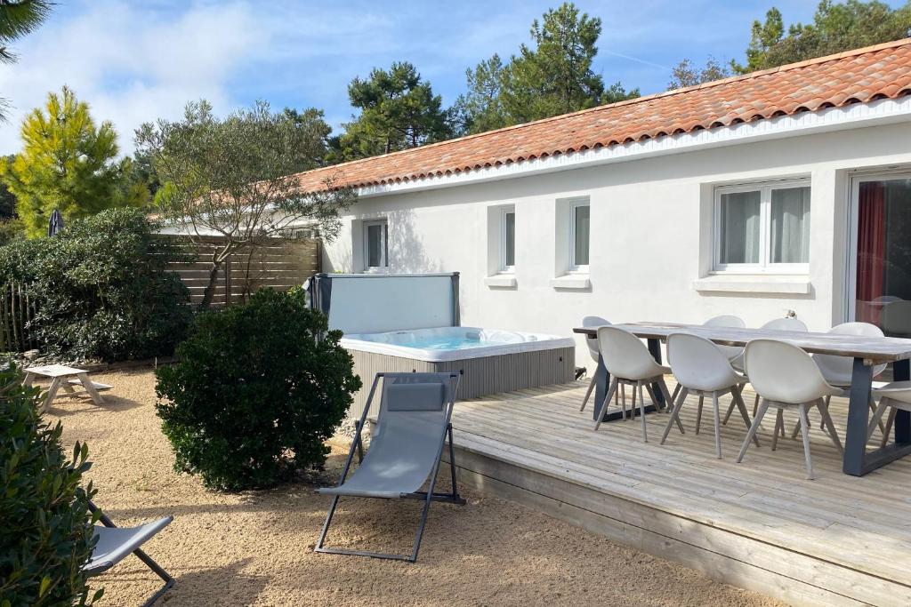 un patio con tavolo e sedie su un ponte di Villa Russie - Domaine Le Sherwood a Notre-Dame-de-Monts