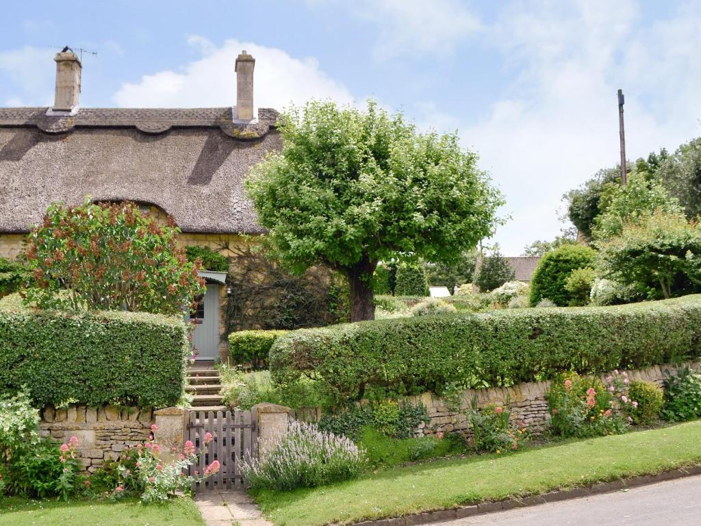 an old stone house with a fence and flowers at Rose Cottage in Chipping Campden